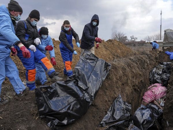 Dead bodies are placed into a mass grave on the outskirts of Mariupol, Ukraine, Wednesday, March 9, 2022 as people cannot bury their dead because of the heavy shelling by Russian forces. (AP Photo/Evgeniy Maloletka)
