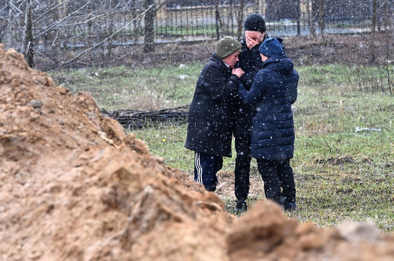 Ukrainians cry as they are looking for their lost loved ones in a mass grave in the Ukrainian town of Bucha